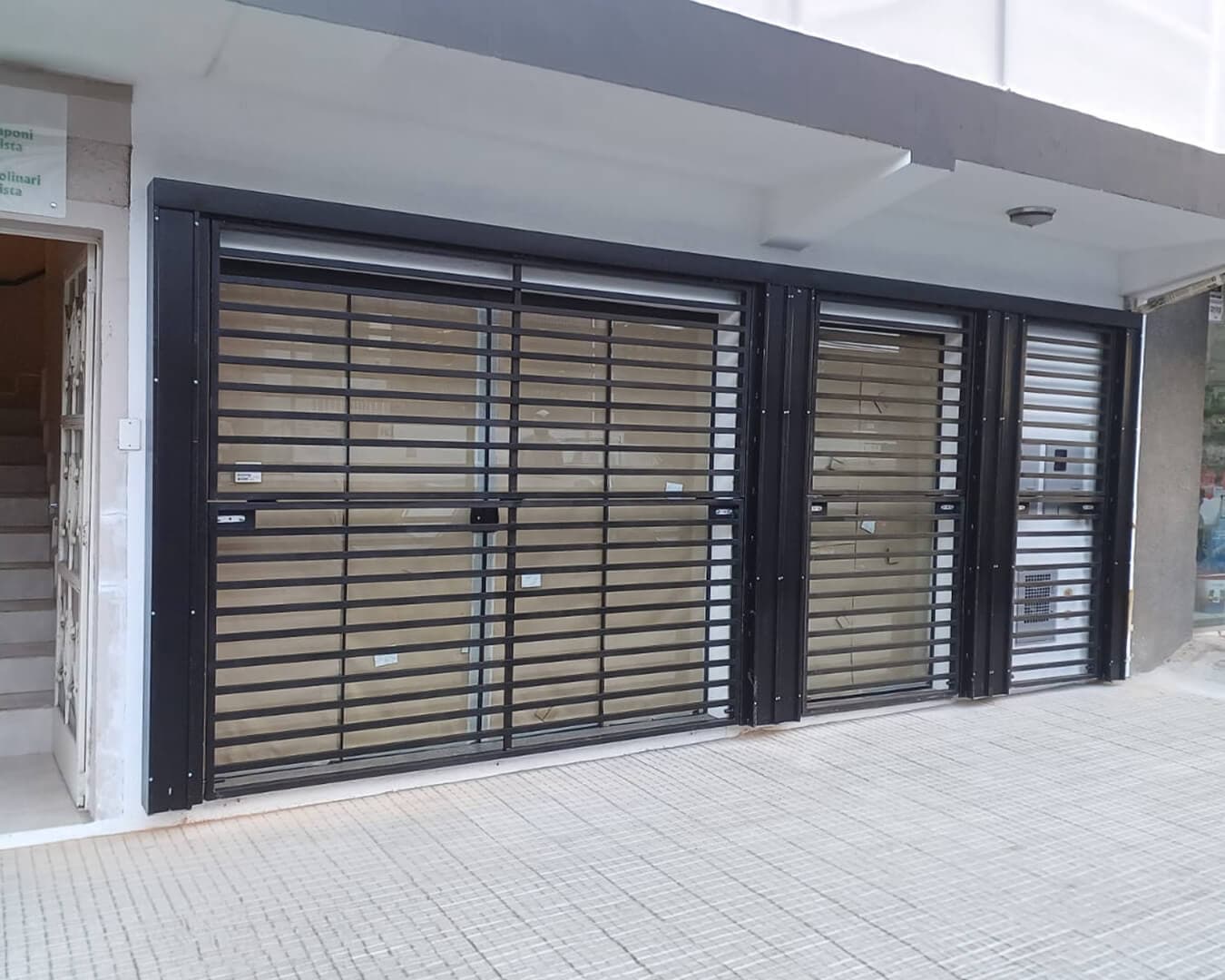 Portões basculantes de grade metálica preta instalados em garagens de prédio comercial