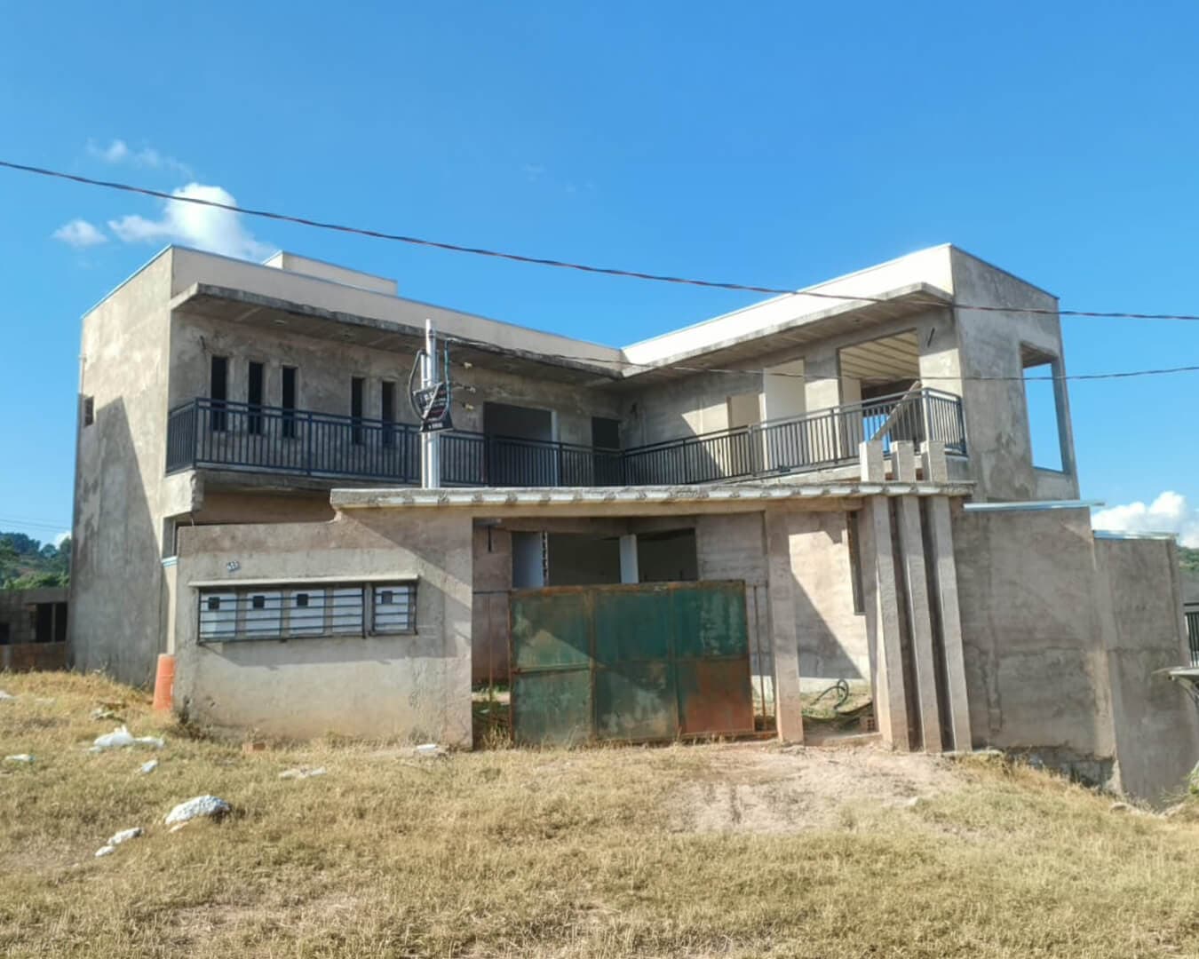 Sobrado em construção com guarda-corpos metálicos nas varandas e portão de metal na fachada